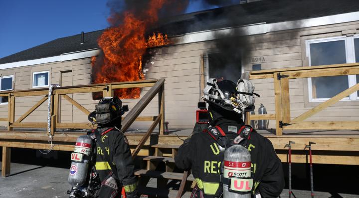 Two firefighters standing outside of a burning structure