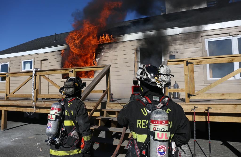 Two firefighters standing outside of a burning structure