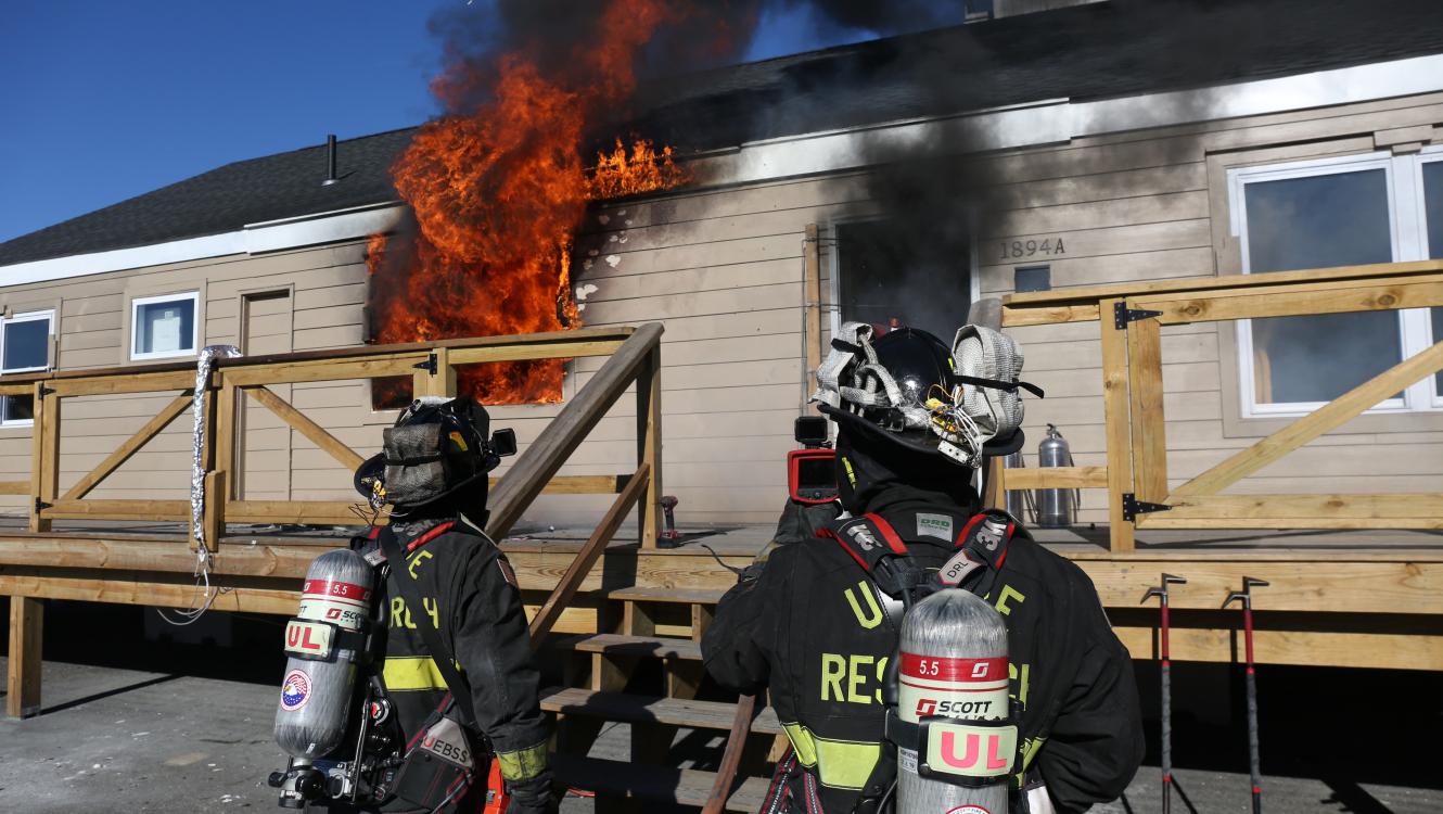 Two firefighters standing outside of a burning structure