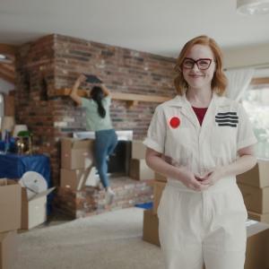 woman dressed as a smoke alarm with couple unpacking boxes in the background