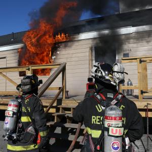Two firefighters standing outside of a burning structure