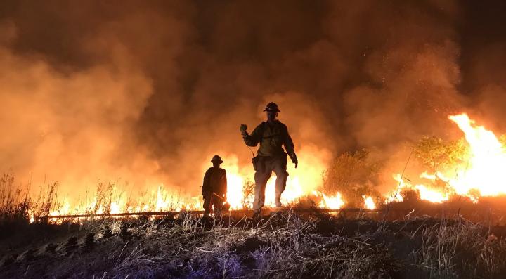 shot showcasing firefighters  along fire line with flames[Photo Credit: West Metro Fire Rescue]