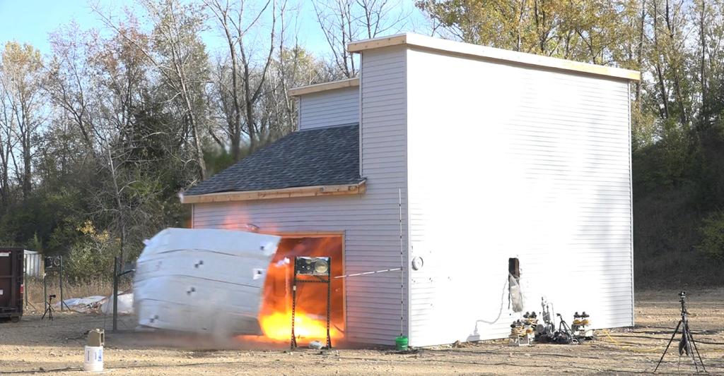 Garage door is blown off of test structure following explosion as a result of thermal runaway test.