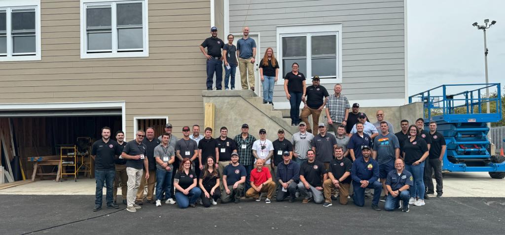Group photo of the technical panel members and FSRI staff standing in front of the townhome and rowhome built for this project in Sharon Hill, PA