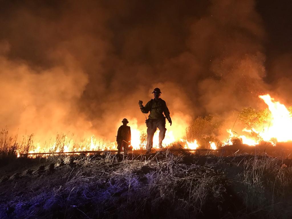 shot showcasing firefighters  along fire line with flames[Photo Credit: West Metro Fire Rescue]