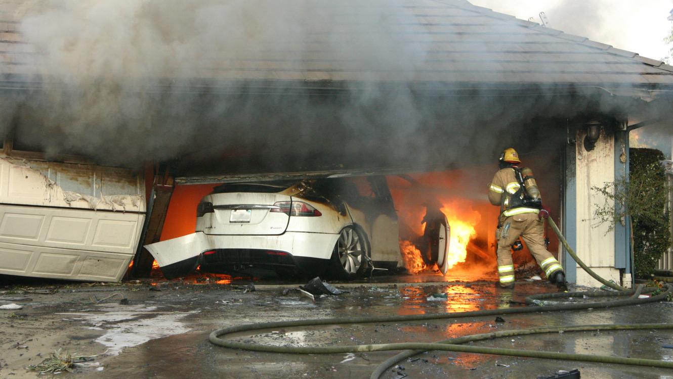 Firefighter onsite at an electric vehicle fire in a residential garage (Photo courtesy of National Transportation Safety Board)