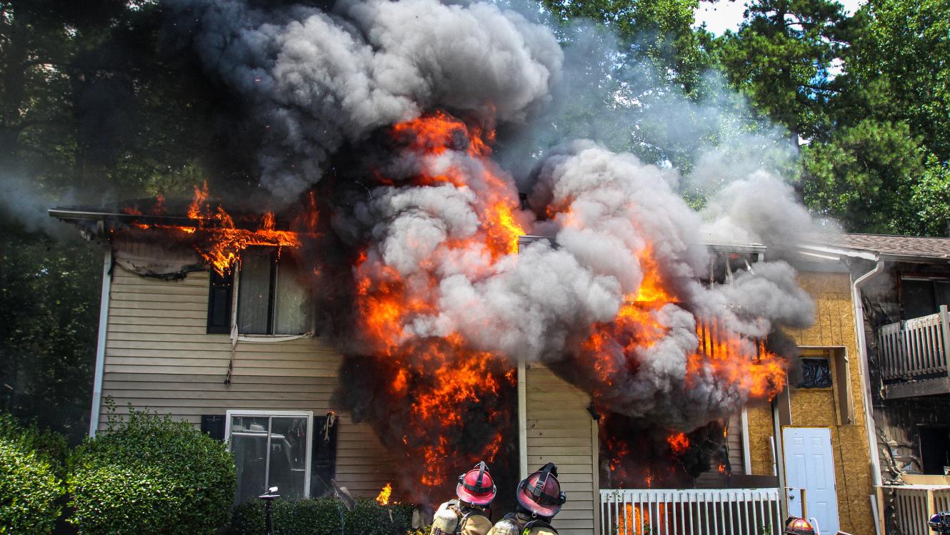 Firefighters standing out a burning house, putting out fire