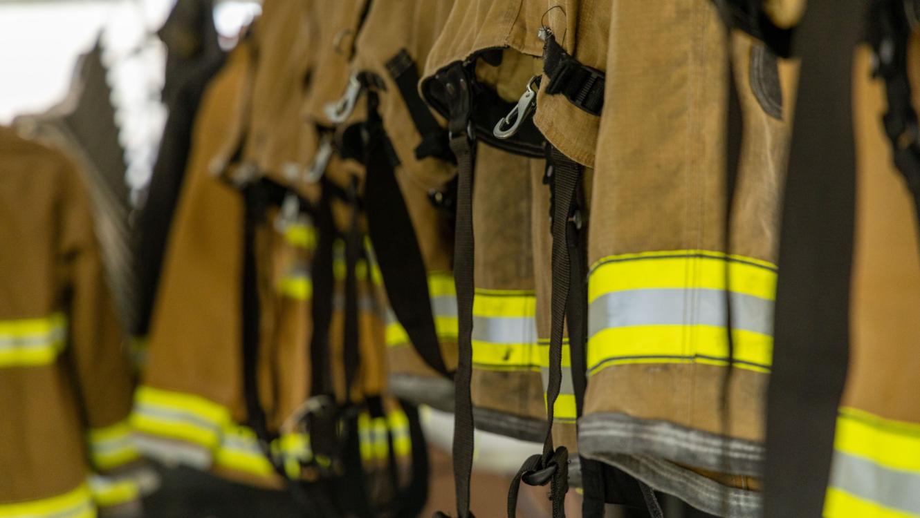 Close-up view of a row of firefighter coats hanging side-by-side