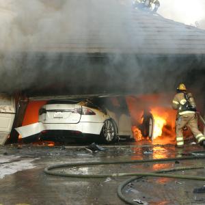 Firefighter onsite at an electric vehicle fire in a residential garage (Photo courtesy of National Transportation Safety Board)