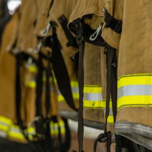 Close-up view of a row of firefighter coats hanging side-by-side